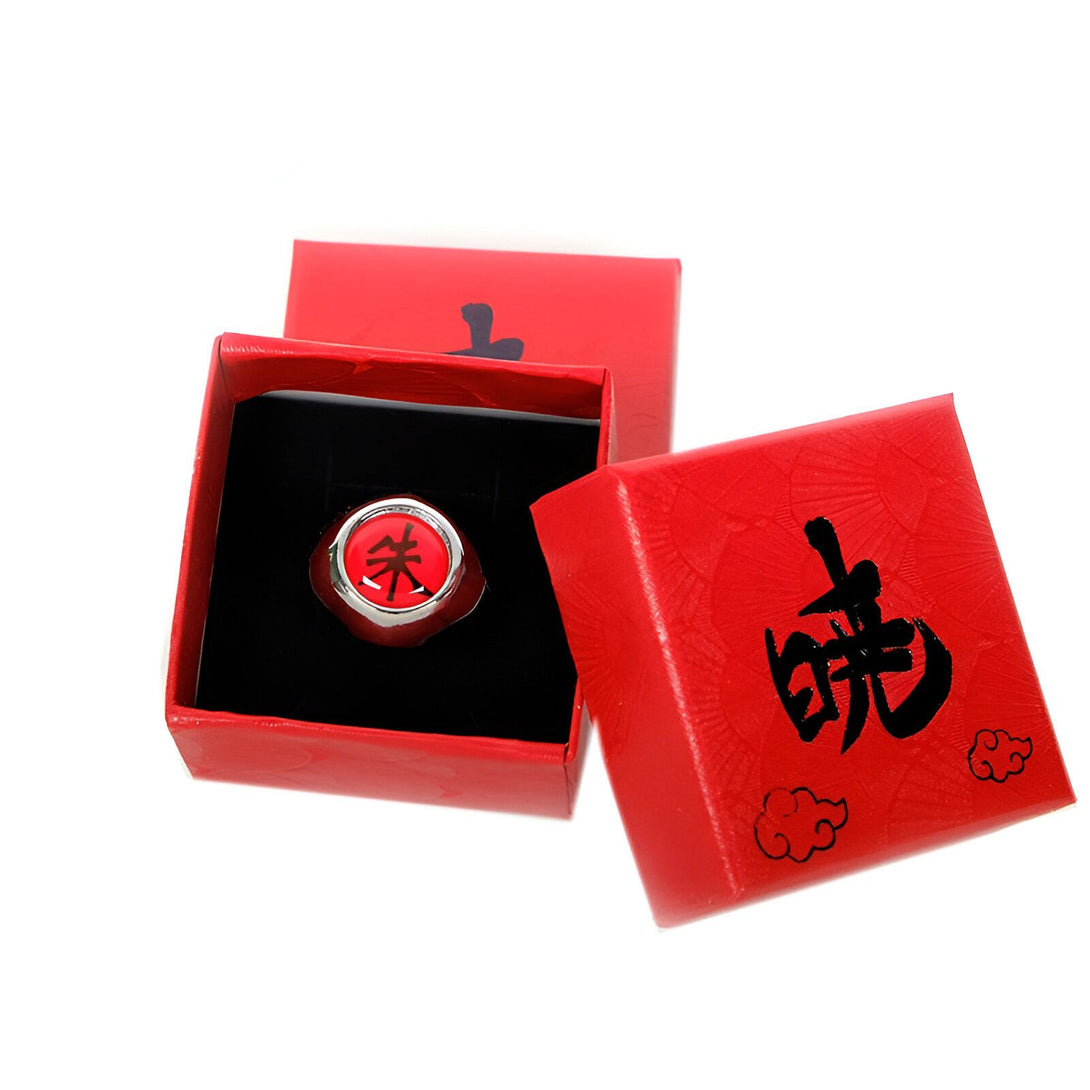 Bague Naruto en métal argenté avec un symbole rouge dans une boîte rouge. La boîte est décorée de nuages et du kanji "Shinobi".