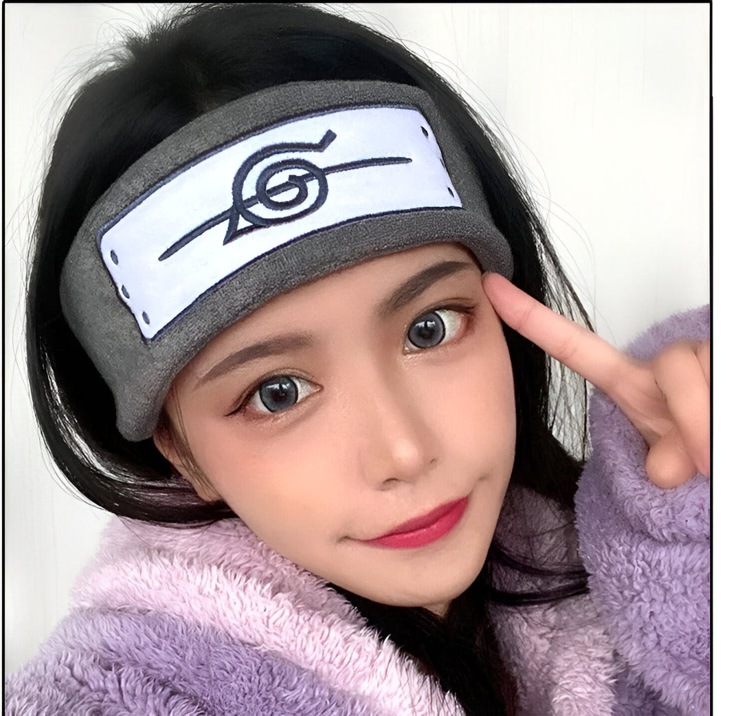 Une jeune femme porte un bandeau gris avec le symbole du village caché des feuilles de Konoha, un accessoire populaire de l'anime Naruto.  Ce bandeau est un excellent cadeau pour les fans de Naruto.