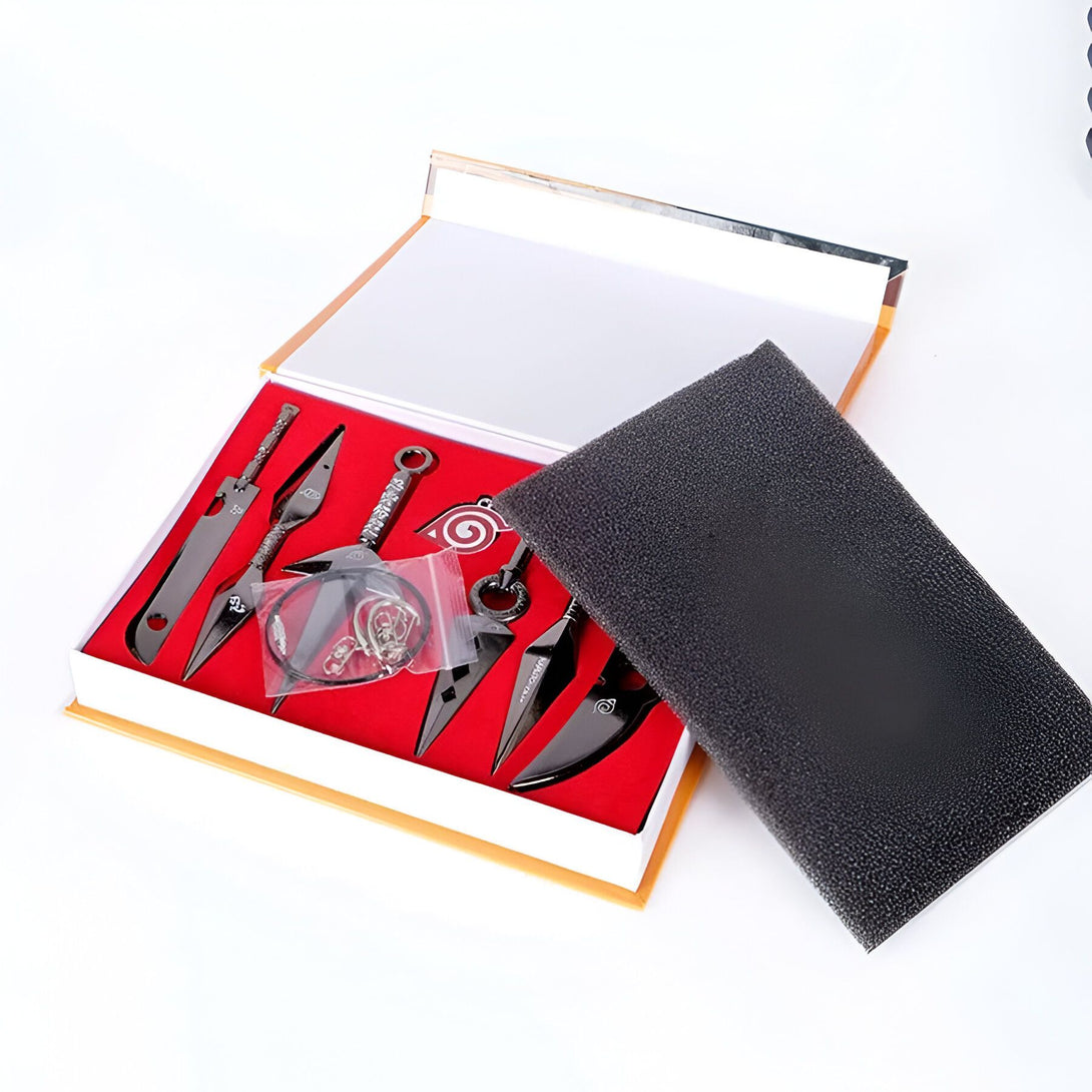 Ensemble de six kunai en métal noir et un pendentif Akatsuki pour les fans de Naruto.  L'ensemble est présenté dans une boîte de présentation élégante avec un rembourrage en mousse.  Le kunai est un outil de combat essentiel dans l'univers de Naruto.