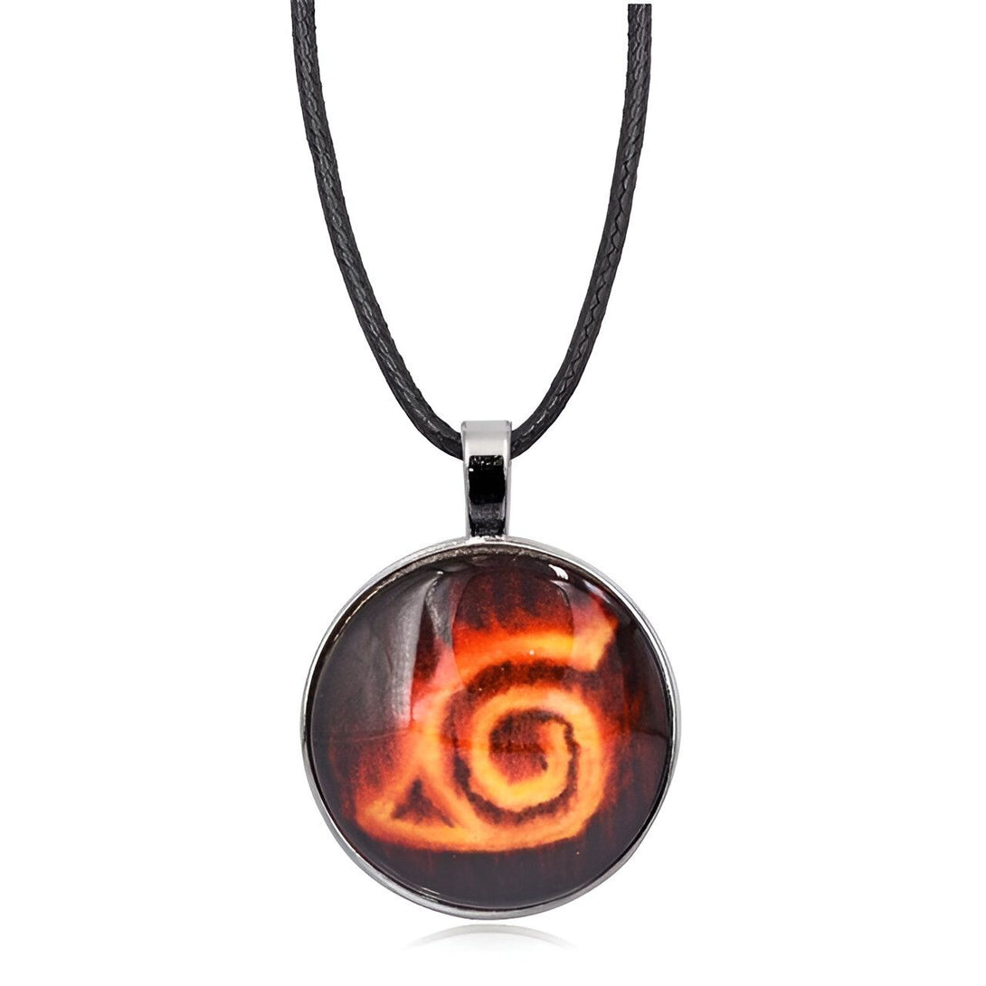 Collier Naruto avec pendentif rond en métal argenté orné du symbole de Konoha, le village caché dans les feuilles. Le symbole est représenté en jaune sur fond rouge, le tout sur un fond noir.