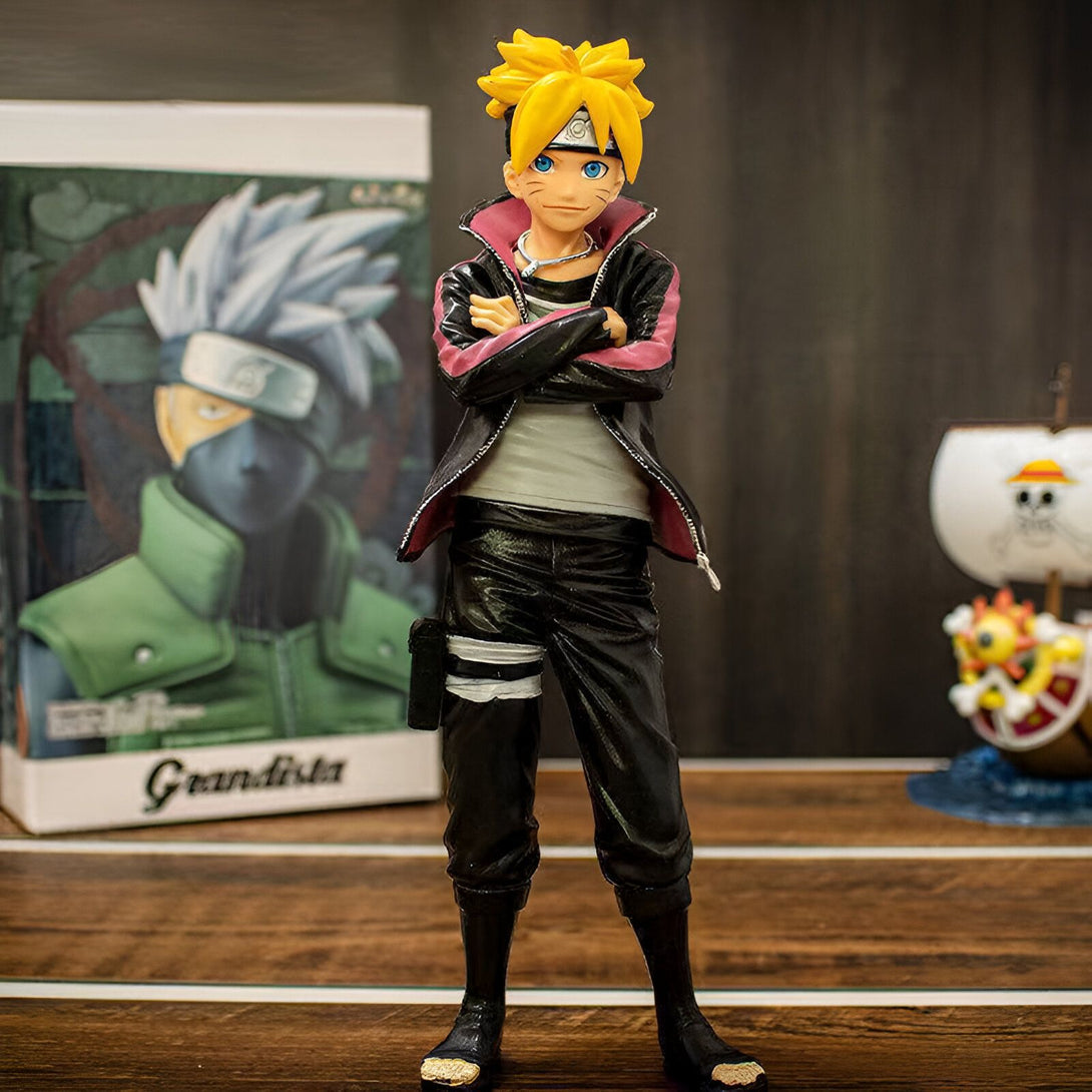 Naruto, un personnage de l'anime Naruto Shippuden, portant une veste rouge et noire, se tient les bras croisés. Il est debout sur une table en bois, avec une boîte de personnage d'anime et une figurine de navire en arrière-plan.