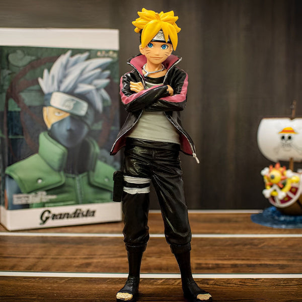 Naruto, un personnage de l'anime Naruto Shippuden, portant une veste rouge et noire, se tient les bras croisés. Il est debout sur une table en bois, avec une boîte de personnage d'anime et une figurine de navire en arrière-plan.