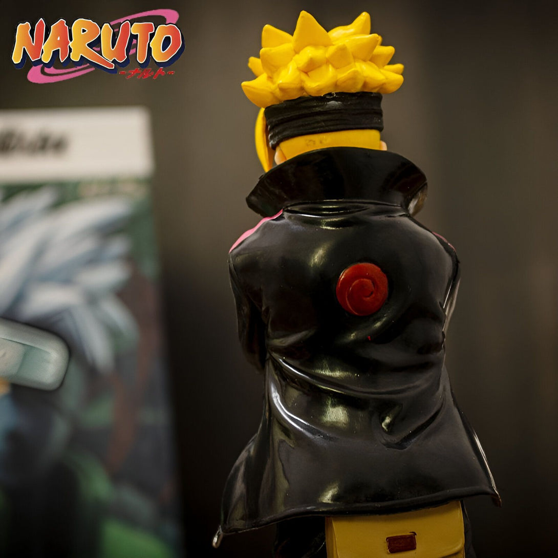 Naruto, personnage de l'anime japonais, vêtu d'un manteau noir avec le symbole du clan Uzumaki sur le dos, se tient debout devant un poster.