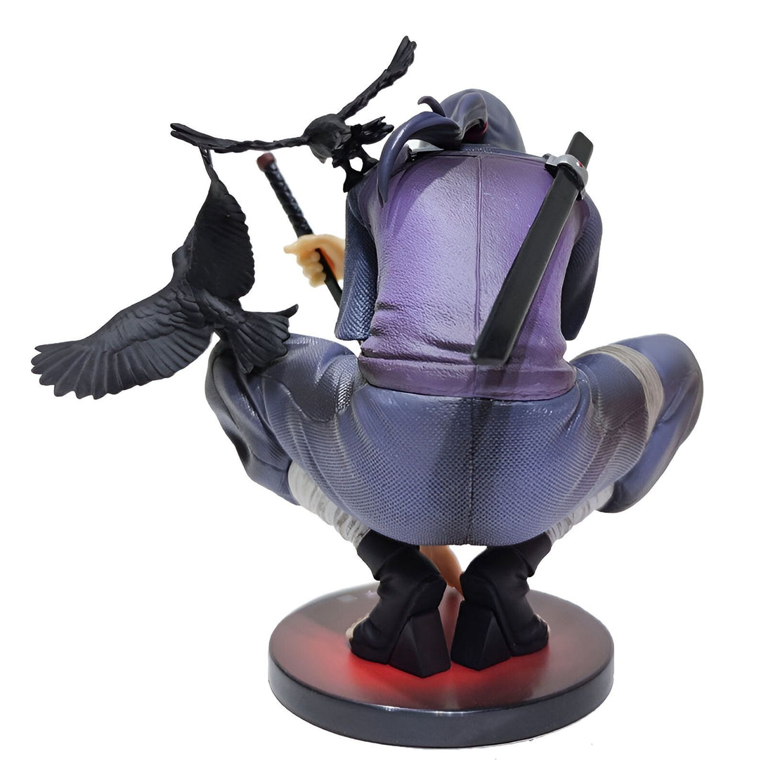Figur de collection de Sasuke Uchiha de Naruto, en position accroupie, tenant un bâton avec deux corbeaux noirs à ses côtés.