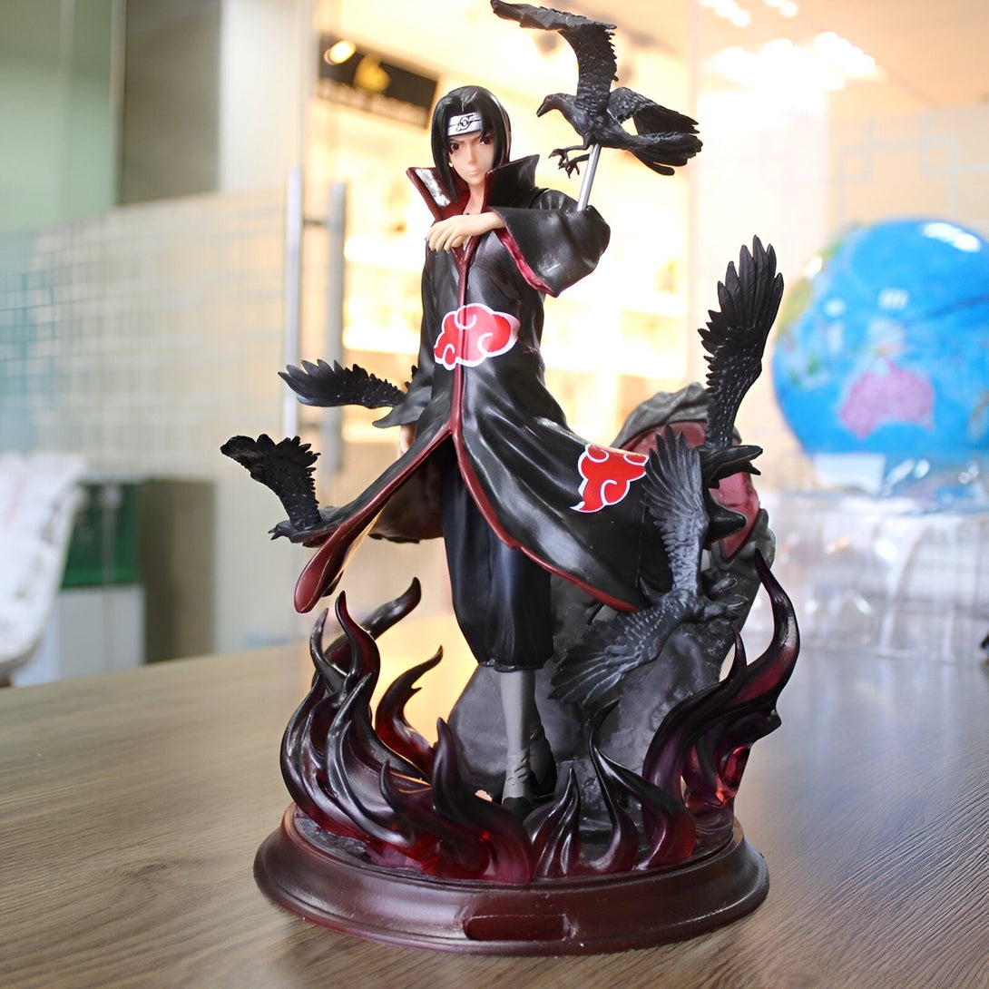 Statue de l'anime Naruto représentant Itachi Uchiwa, portant son manteau Akatsuki rouge et noir, debout sur un socle de flammes avec des corbeaux autour de lui.