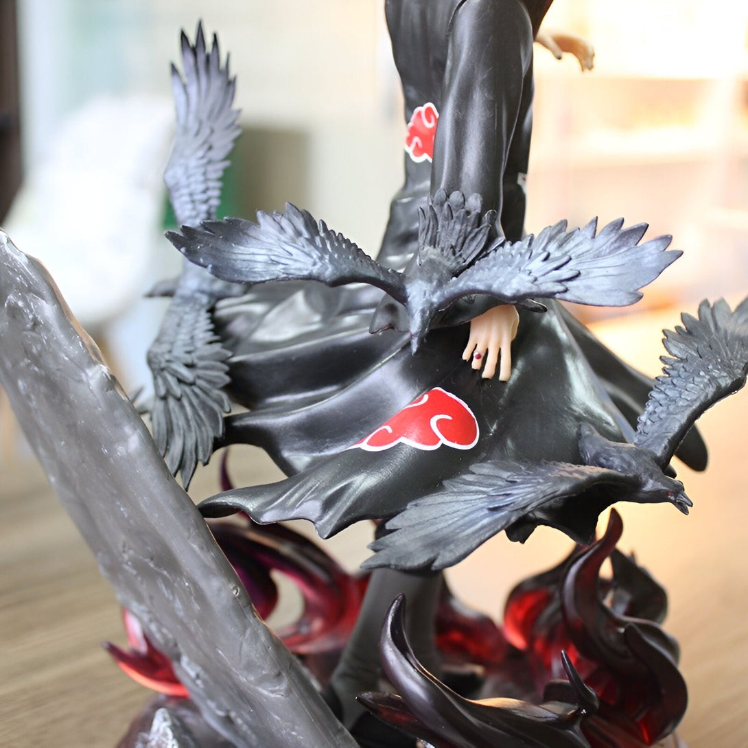 Statue de figurines de collection de Naruto, représentant Obito Uchiwa avec le Sharingan et entouré de corbeaux, sur un socle avec des flammes rouges.