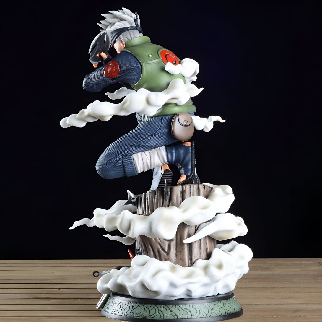 Statue de Kakashi Hatake, personnage de l'anime Naruto, dans une pose dynamique avec des effets de fumée. La figurine est placée sur un socle en bois avec une base ornée de motifs.
