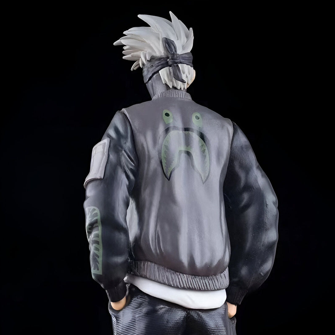 Figure de Naruto portant un blouson gris avec un logo de requin vert sur le dos. Il porte également un bandeau sur la tête.  La figurine est sur fond noir.