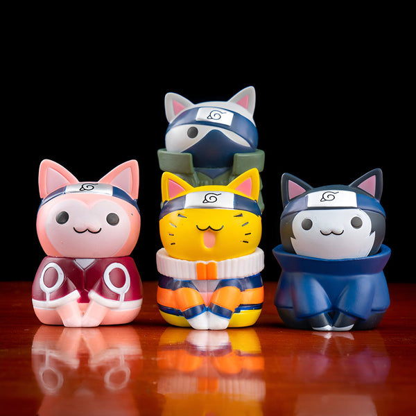Quatre figurines de chat Naruto portant des bandeaux avec le symbole du village caché de la feuille. Les chats sont habillés comme les personnages de l'anime Naruto: Kakashi, Naruto, Sasuke et Sakura.