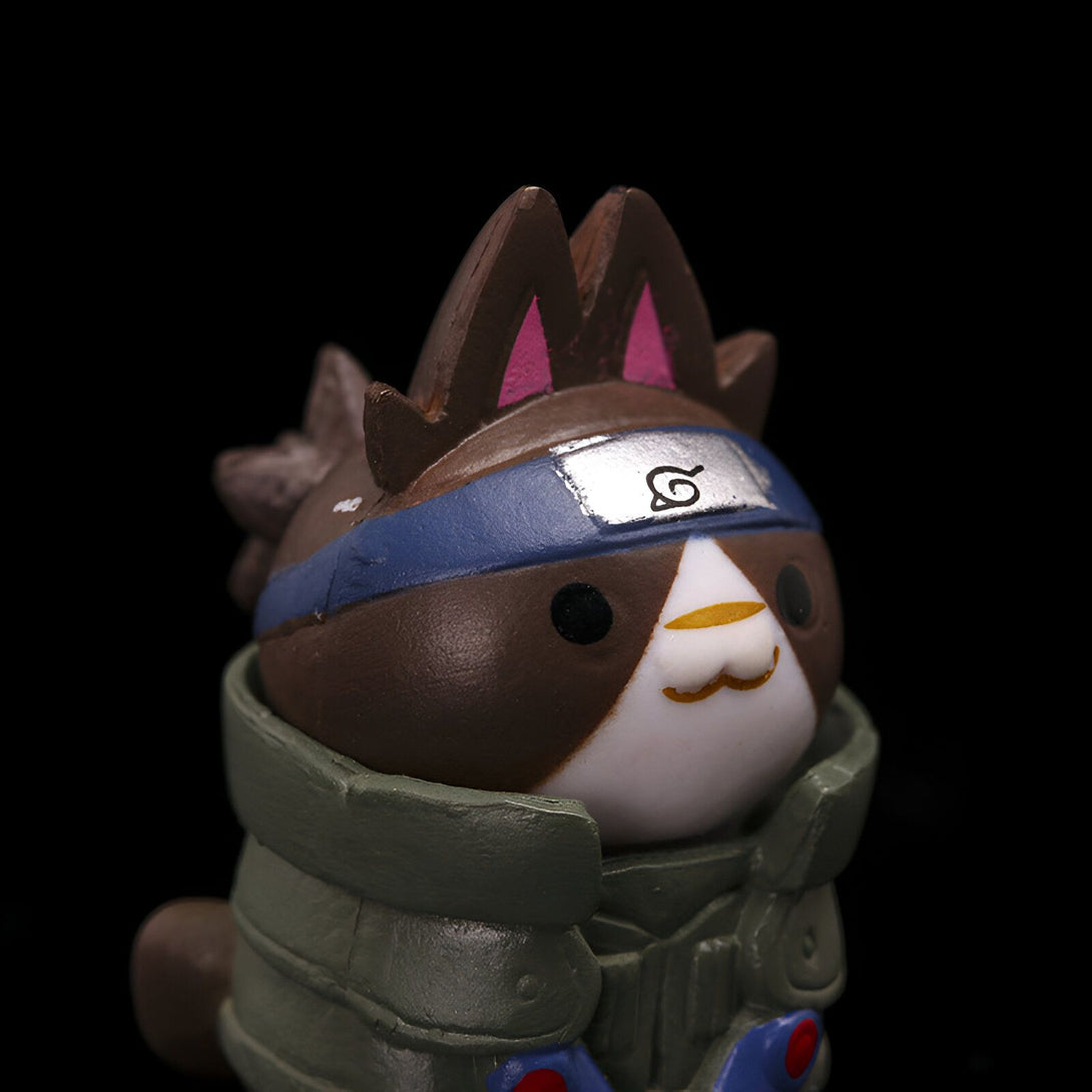 Une figurine de chat portant un bandeau avec le symbole du village caché de la feuille, un symbole important dans l'anime Naruto. Cette figurine est un excellent cadeau pour les fans de Naruto.