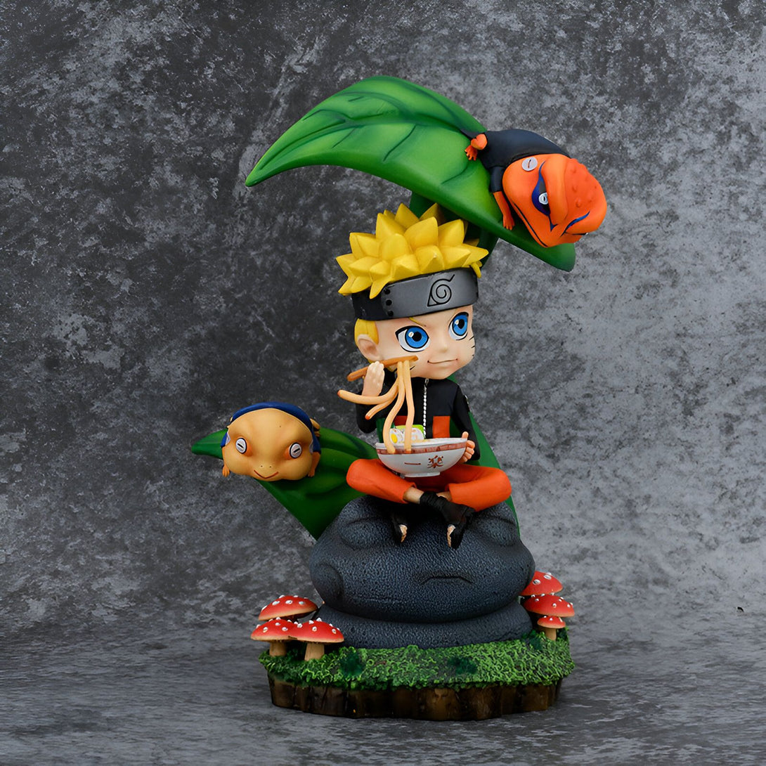 Naruto Uzumaki, le célèbre ninja de Konoha, est assis sur un rocher et mange des ramen. Il est accompagné de ses deux crapauds, Gamakichi et Gamabunta, qui le regardent avec affection. Cette figurine représente un moment tendre de l'univers Naruto, parfait pour les fans de la série.