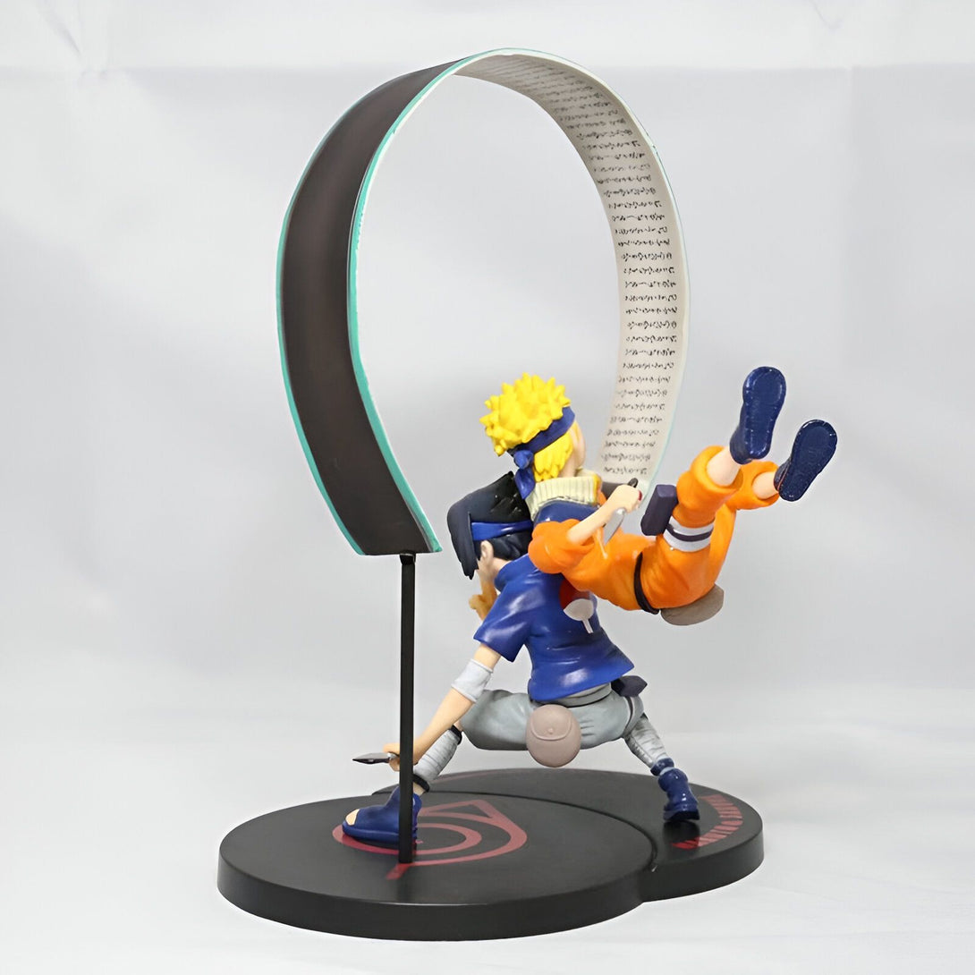 Naruto et Sasuke, les personnages principaux de la série manga et anime Naruto, dans une figurine de collection. Naruto est en jaune et bleu, tandis que Sasuke porte une veste bleue et une chemise blanche. La figurine est posée sur une base circulaire noire ornée du symbole du village caché de Konoha.