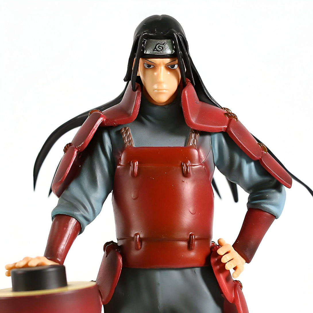 Figure de collection de  Hidan, un personnage du manga Naruto, portant son armure rouge et ses cheveux longs noirs.  Il porte également un bandeau frontal avec le symbole du village caché de la pluie.