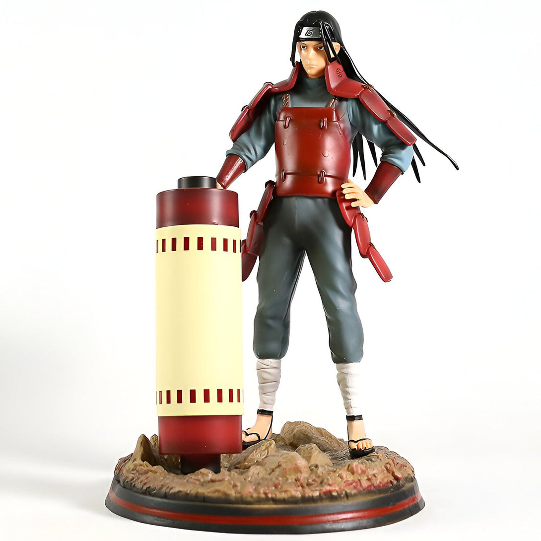 Figur de Hidan de Naruto Shippuden en position de combat, tenant un rouleau de parchemin rouge et debout sur une base rocheuse.