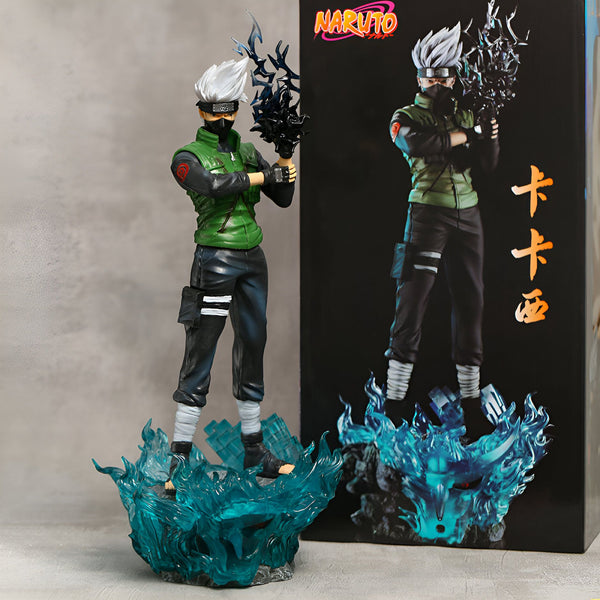 Figurine de collection de Kakashi Hatake de Naruto, debout sur un socle avec des flammes bleues, tenant son Sharingan dans sa main. La figurine est présentée à côté de sa boîte d'emballage.
