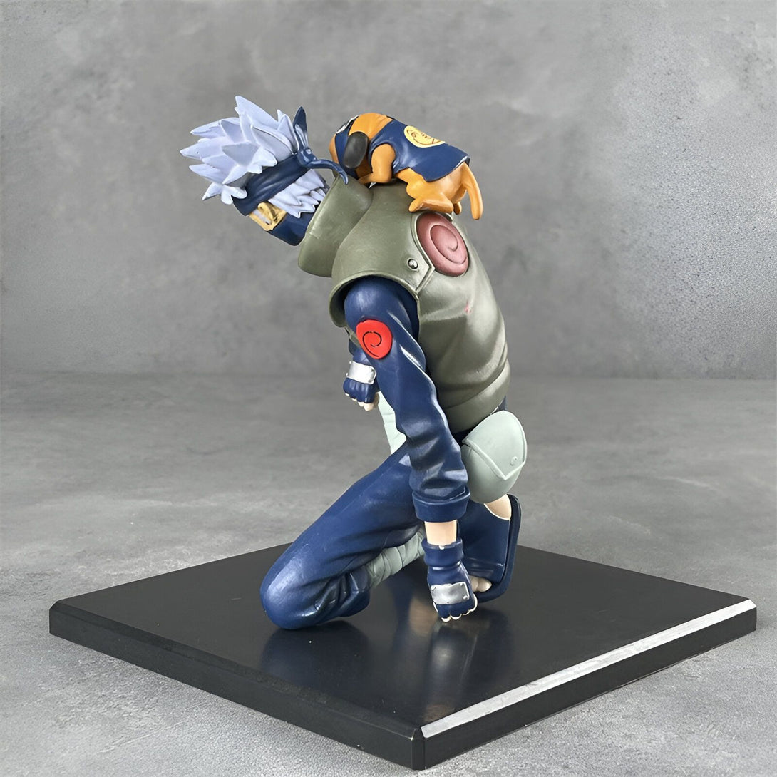 Figur de Kakashi Hatake, un personnage populaire de l'anime Naruto, représenté en train de s'agenouiller avec Pakkun, son chien ninja, sur son épaule. La figurine est peinte avec des détails précis et est posée sur un socle noir.