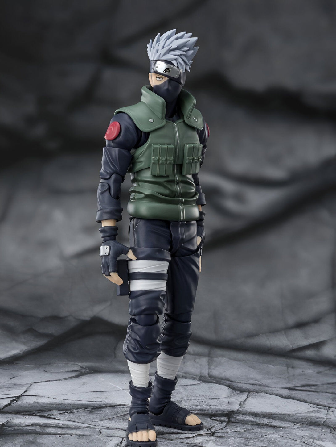 Figurine de Kakashi Hatake, un personnage de l'anime Naruto, portant son costume vert et noir emblématique.  Il tient un couteau dans sa main gauche et est prêt à l'action.  Parfait pour les fans de Naruto !