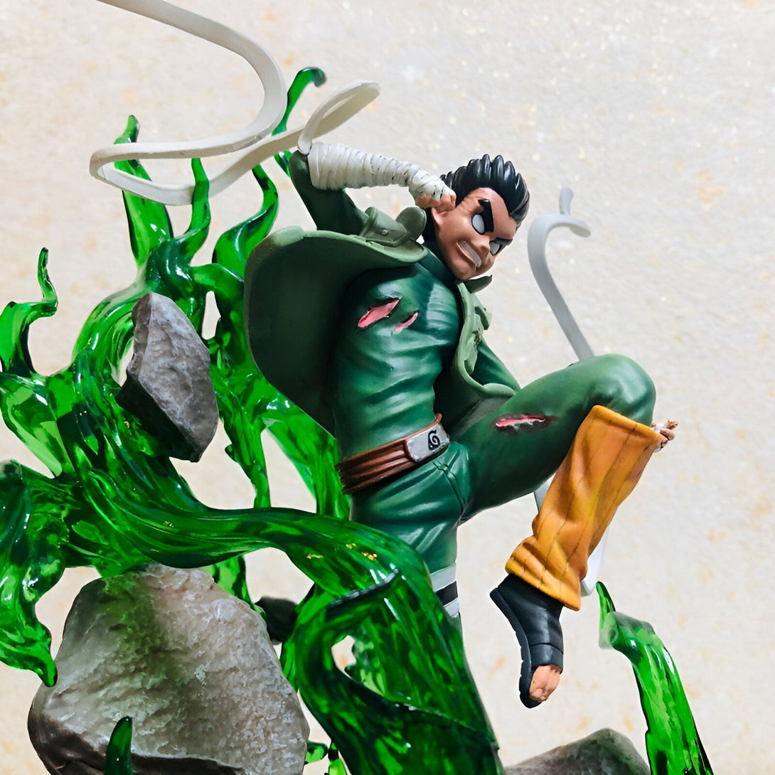 Figure de Rock Lee en action, portant son uniforme vert et ses bandages, en train d'utiliser ses techniques de taijutsu. La figurine est posée sur une base avec des effets verts représentant sa technique de ninja.