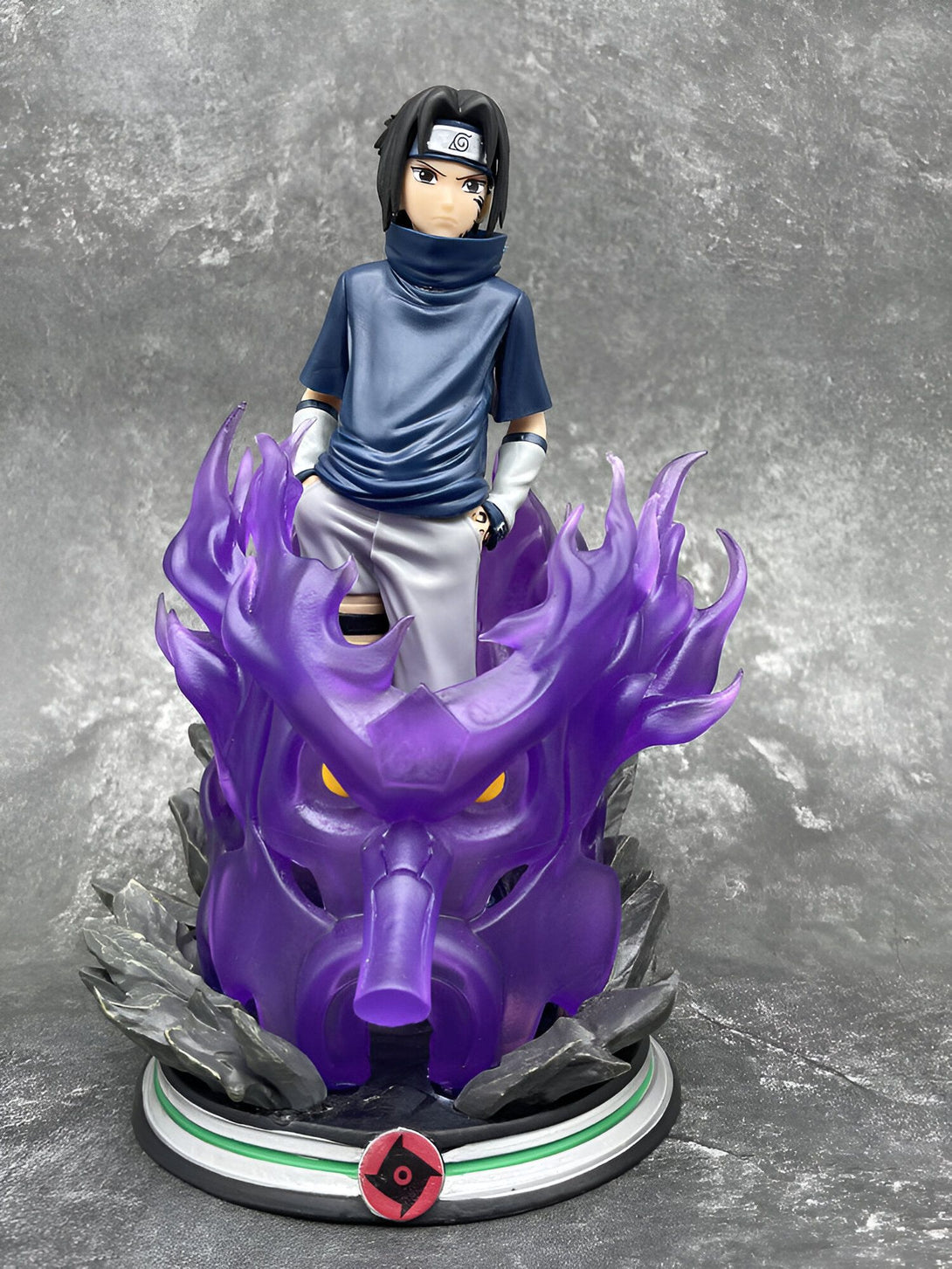 Statue de Naruto Uzumaki, le héros de l'anime Naruto, debout sur une base représentant le visage du démon renard à neuf queues. La statue est peinte avec des couleurs vives et représente le personnage avec précision.
