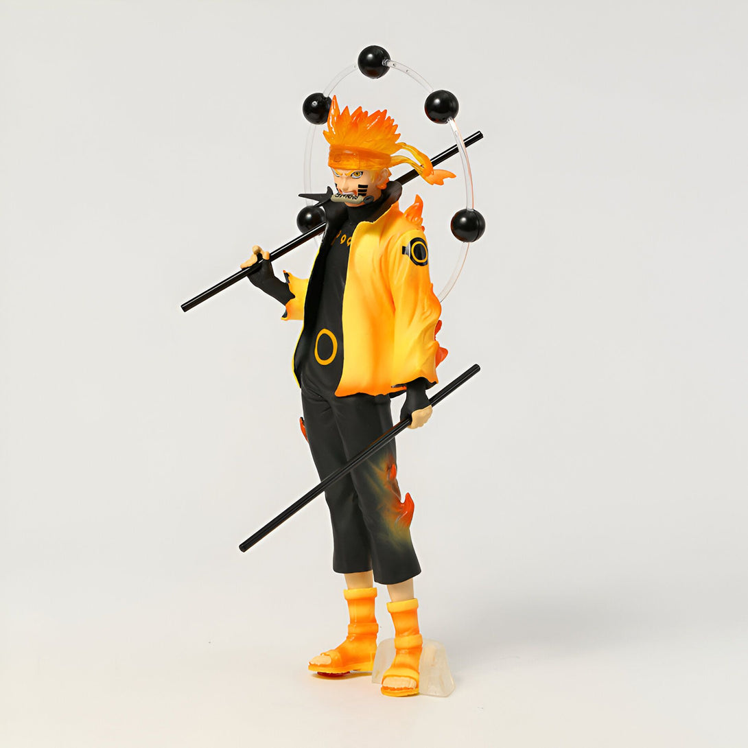 Naruto Uzumaki, le célèbre personnage de l'anime Naruto, dans sa forme de "Kurama" avec ses chakra enflammés. Il tient deux katanas et porte une veste jaune avec le symbole du clan Uzumaki. La figurine est posée sur un socle.