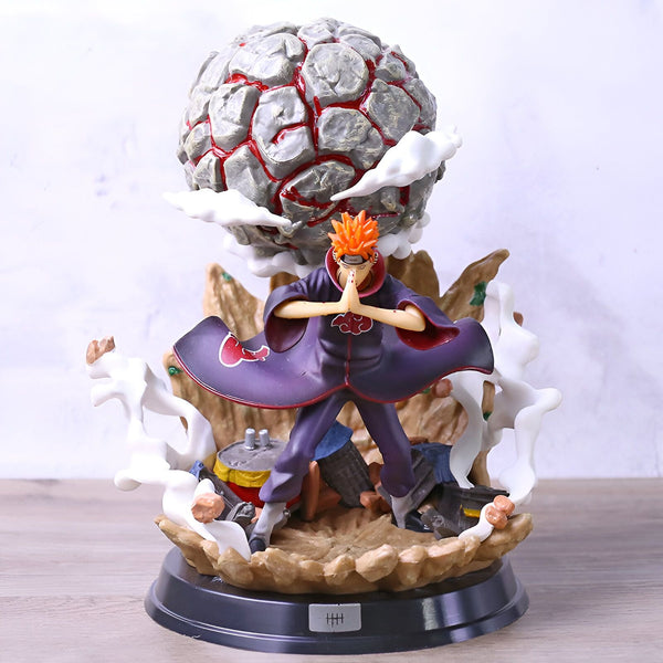 Statue de Pain, personnage de l'anime Naruto, en train de lancer sa technique "Shinra Tensei" avec une sphère de roche géante flottant au-dessus de lui. La figurine est posée sur un socle en forme de roche avec des nuages.