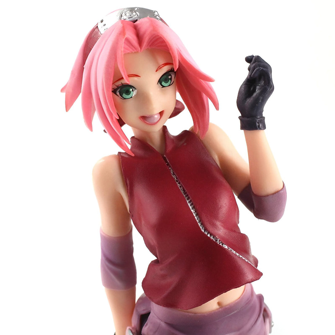 Figurines de collection Naruto : Figurine de Sakura Haruno en tenue rouge et rose avec des cheveux roses, portant un bandeau frontal argenté, souriante et tenant un bandeau noir.