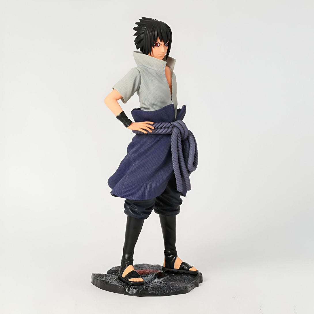Figure de Sasuke Uchiha de l'anime Naruto, debout sur un socle noir, avec son costume bleu et son bandeau rouge.