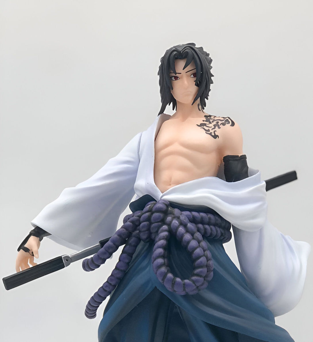 Figurine de Sasuke Uchiha de Naruto Shippuden, portant une tenue de combat blanche et un pantalon bleu. Il tient un katana dans sa main droite.