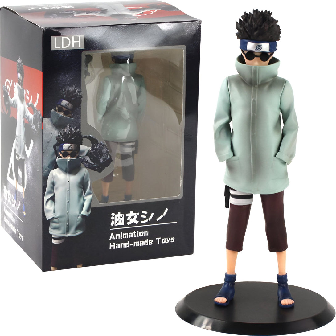Figurines de collection de Naruto Shippuden, représentant un personnage du manga en tenue d'entraînement, avec un manteau vert clair, une bande noire sur le bras et des lunettes.  La figurine est présentée dans une boîte noire avec des détails en rouge et blanc.