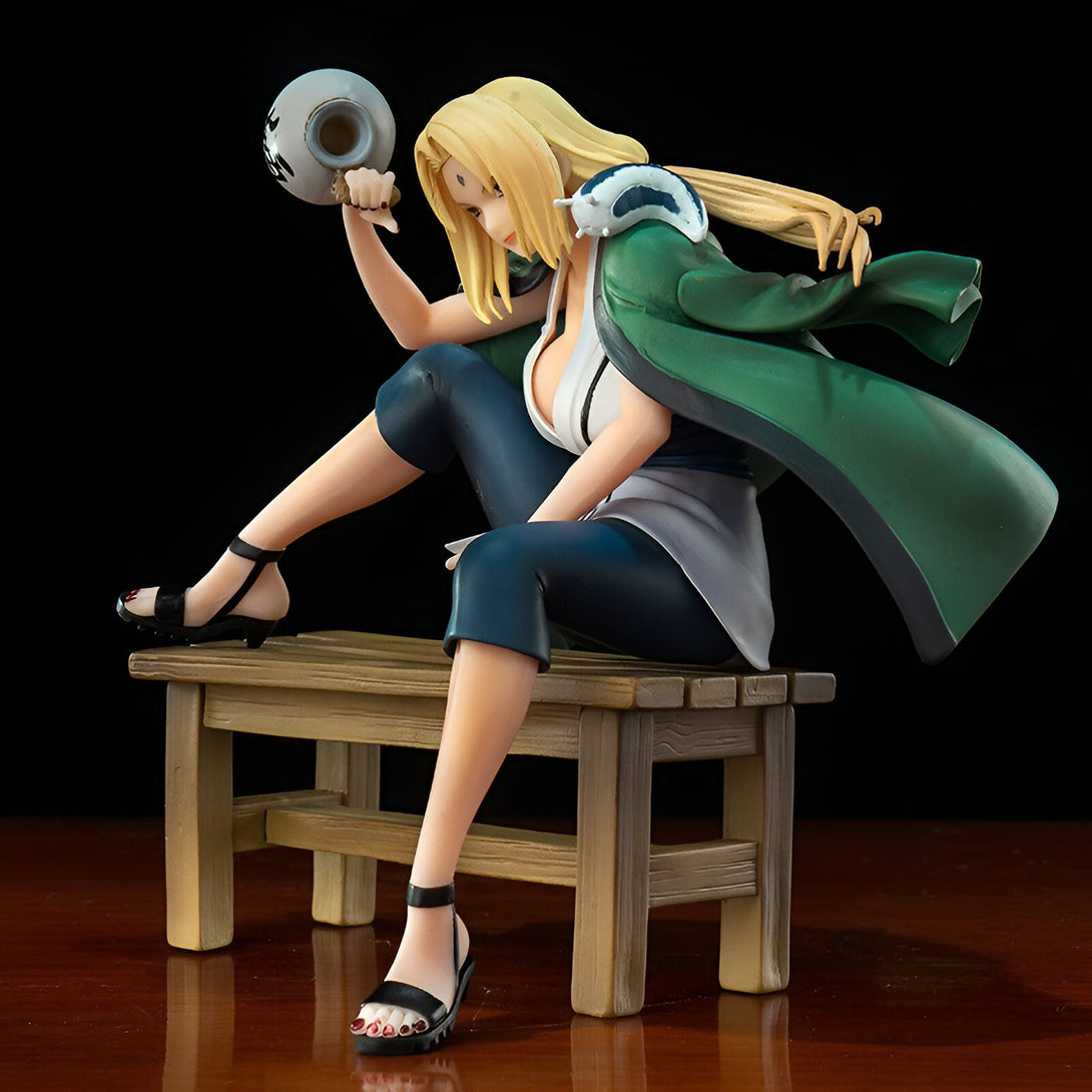 Figure de Tsunade de Naruto Shippuden, la légendaire Hokage du village caché de la Feuille, assise sur un banc en bois avec sa gourde.