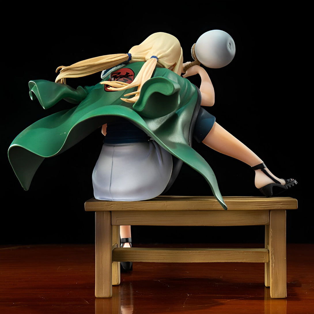 Figur de Tsunade de Naruto Shippuden, assise sur un banc en bois, vêtue d'une robe verte et tenant un énorme gourd.