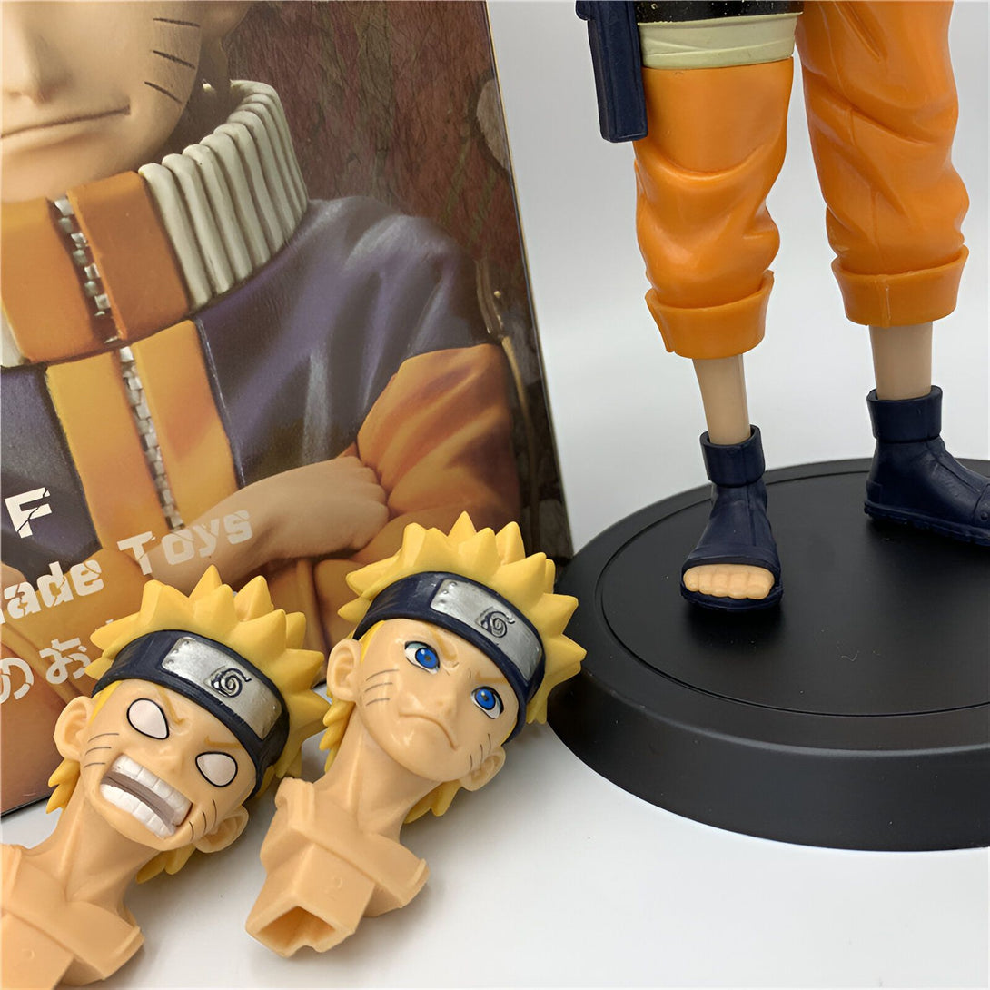 Une figurine de Naruto Uzumaki en action, portant son costume orange emblématique. La figurine est placée sur un socle noir, avec deux têtes de Naruto supplémentaires à côté.  Les têtes de Naruto sont dans des styles différents, offrant aux collectionneurs plusieurs options pour personnaliser leur figurine.