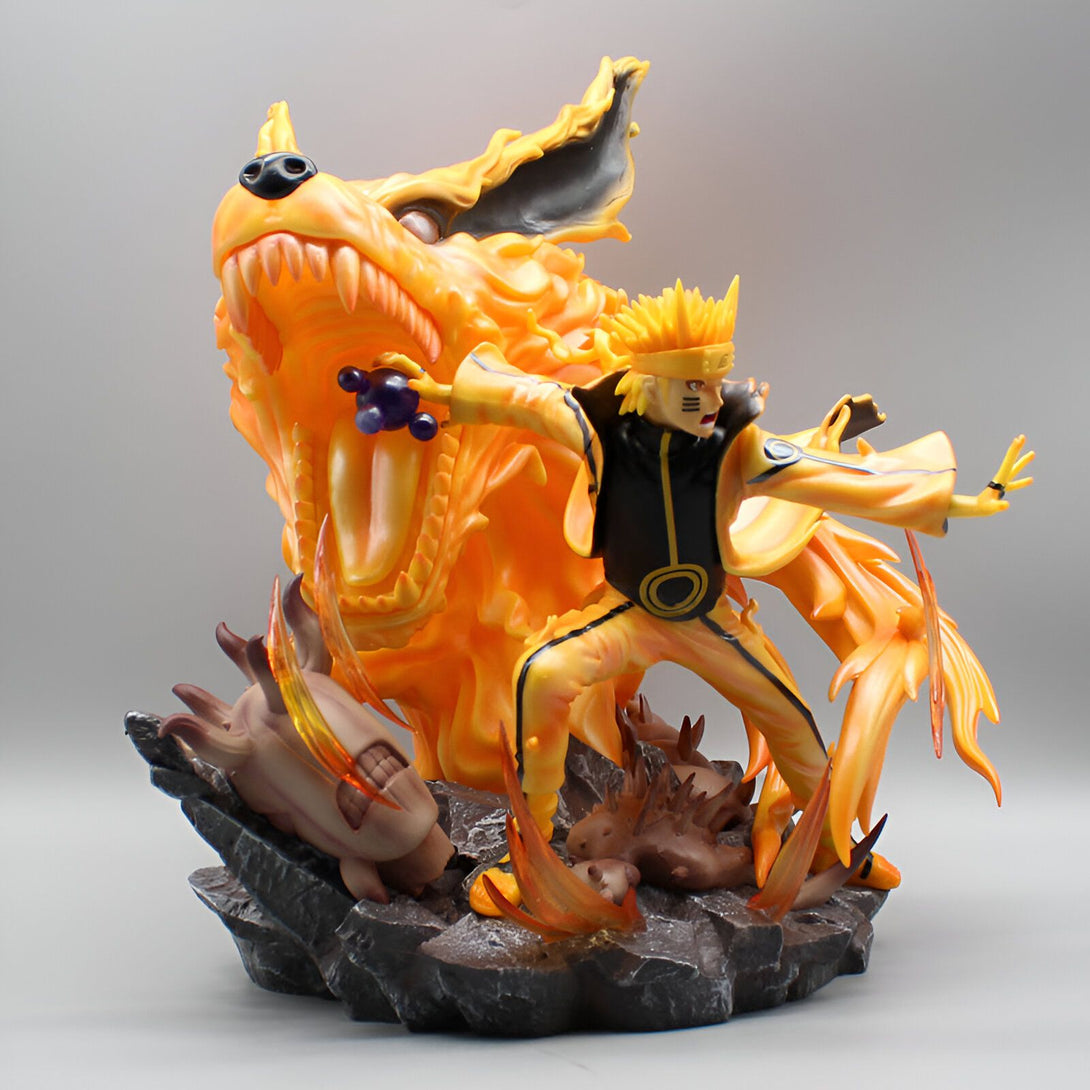 Naruto Uzumaki en mode Kyûbi, dans une pose dynamique, avec Kurama, le démon renard à neuf queues, en arrière-plan. La figurine est posée sur un socle rocheux.