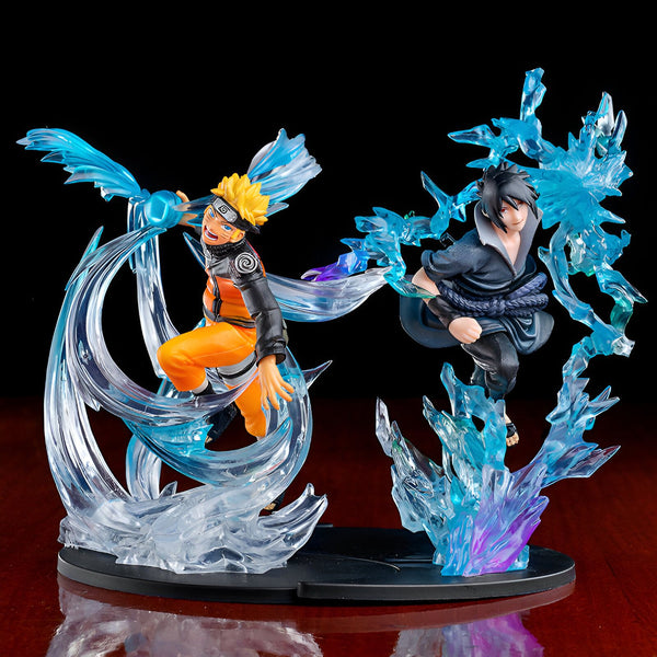 Statue de Naruto et Sasuke en action, entourés d'effets spéciaux de combat en bleu.