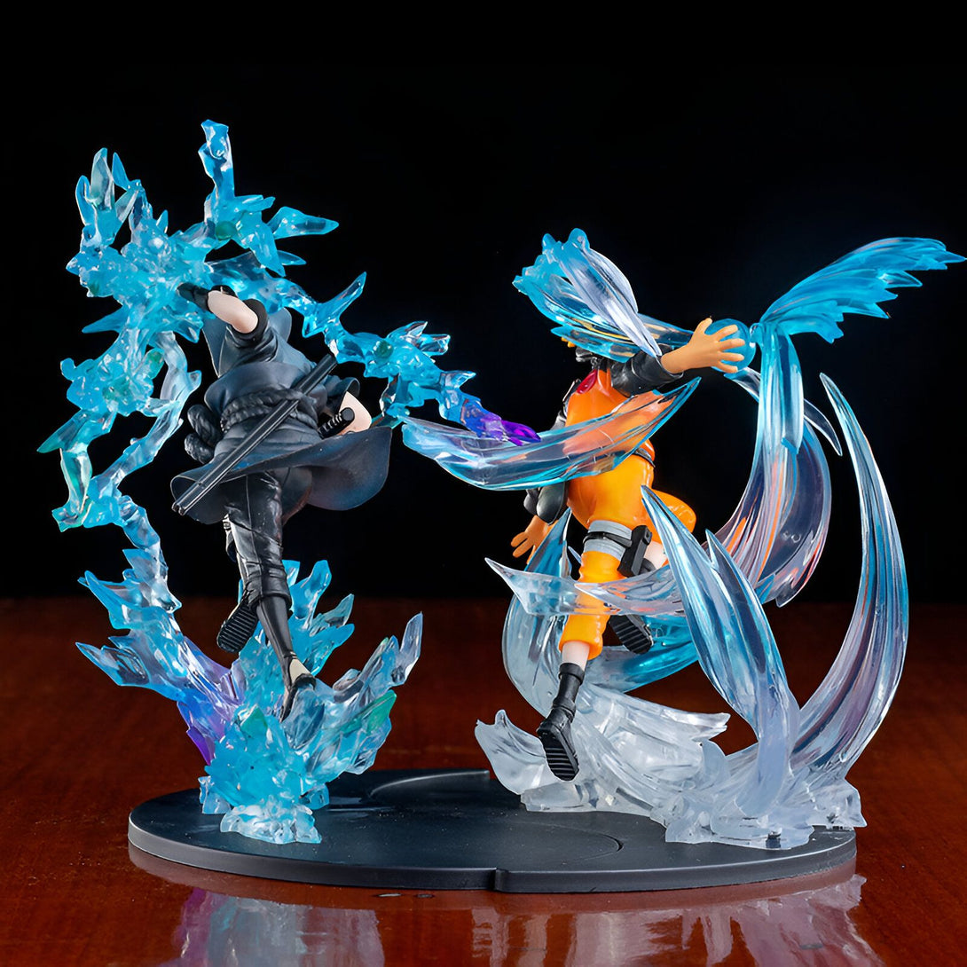 Figurines Naruto et Sasuke en PVC, posant dans une scène dynamique entourés d'effets spéciaux de glace bleue.