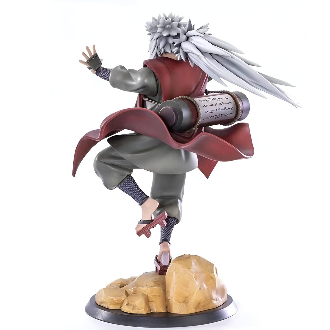 Statue de Jiraiya, personnage de l'anime Naruto, dans une pose dynamique, tenant un parchemin et portant une tenue rouge et verte. La figurine est placée sur une base rocheuse.