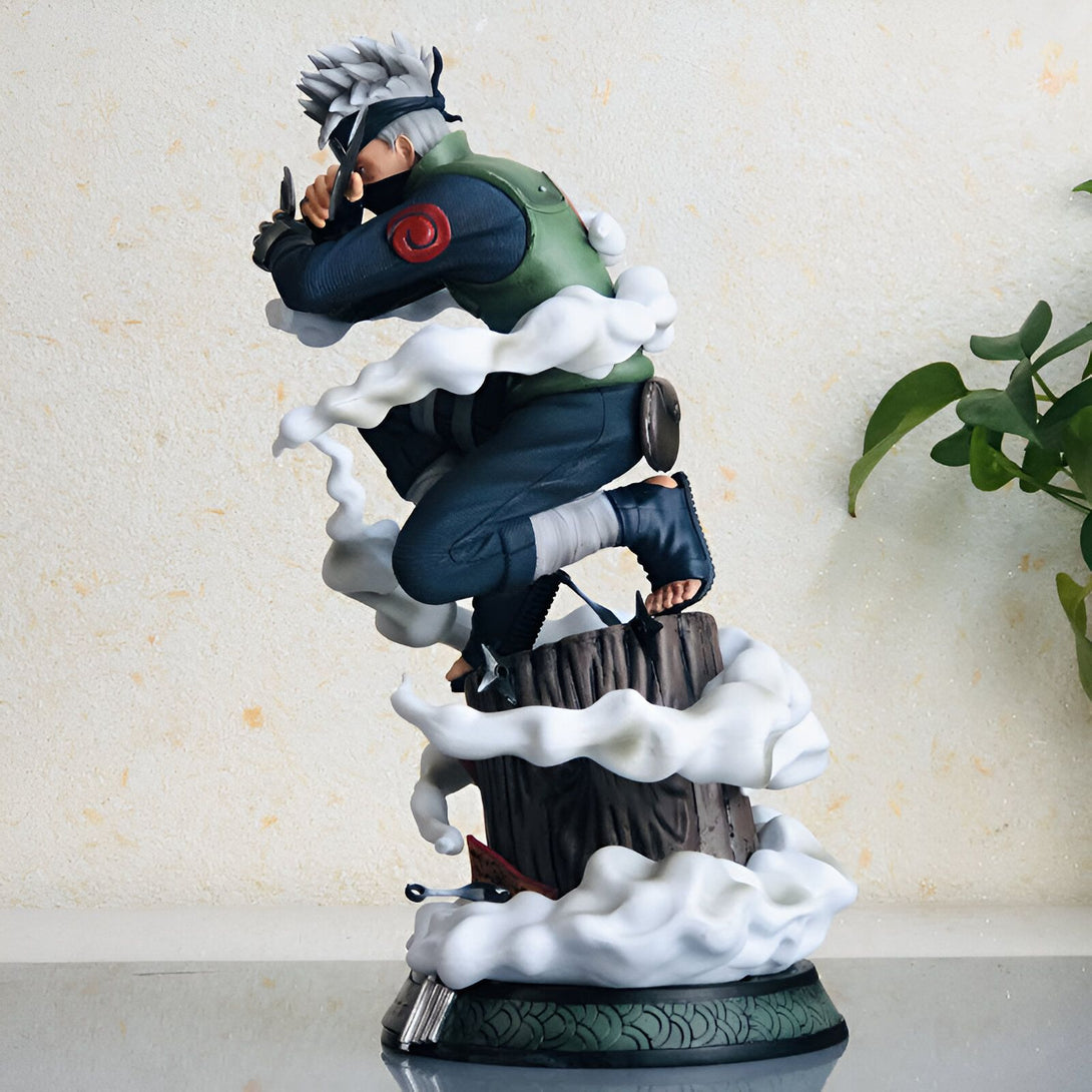 Statue de Kakashi Hatake de Naruto en position de combat, entouré de fumée blanche, sur une souche d'arbre.  La figurine est peinte avec des détails réalistes et représente le personnage emblématique de l'anime Naruto.
