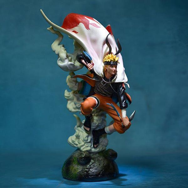 Statue de Naruto Uzumaki en mode Sage des Six Chemins, avec un manteau blanc et rouge, tenant une arme et posant sur un rocher entouré de nuages.