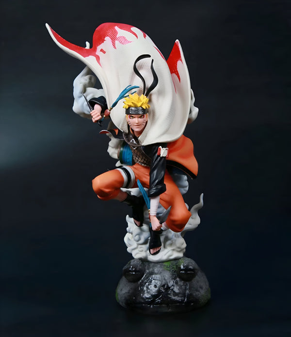 Statue de Naruto Uzumaki en mode Sage des Six Chemins, portant un manteau blanc avec des flammes rouges, tenant deux kunai et debout sur un rocher.