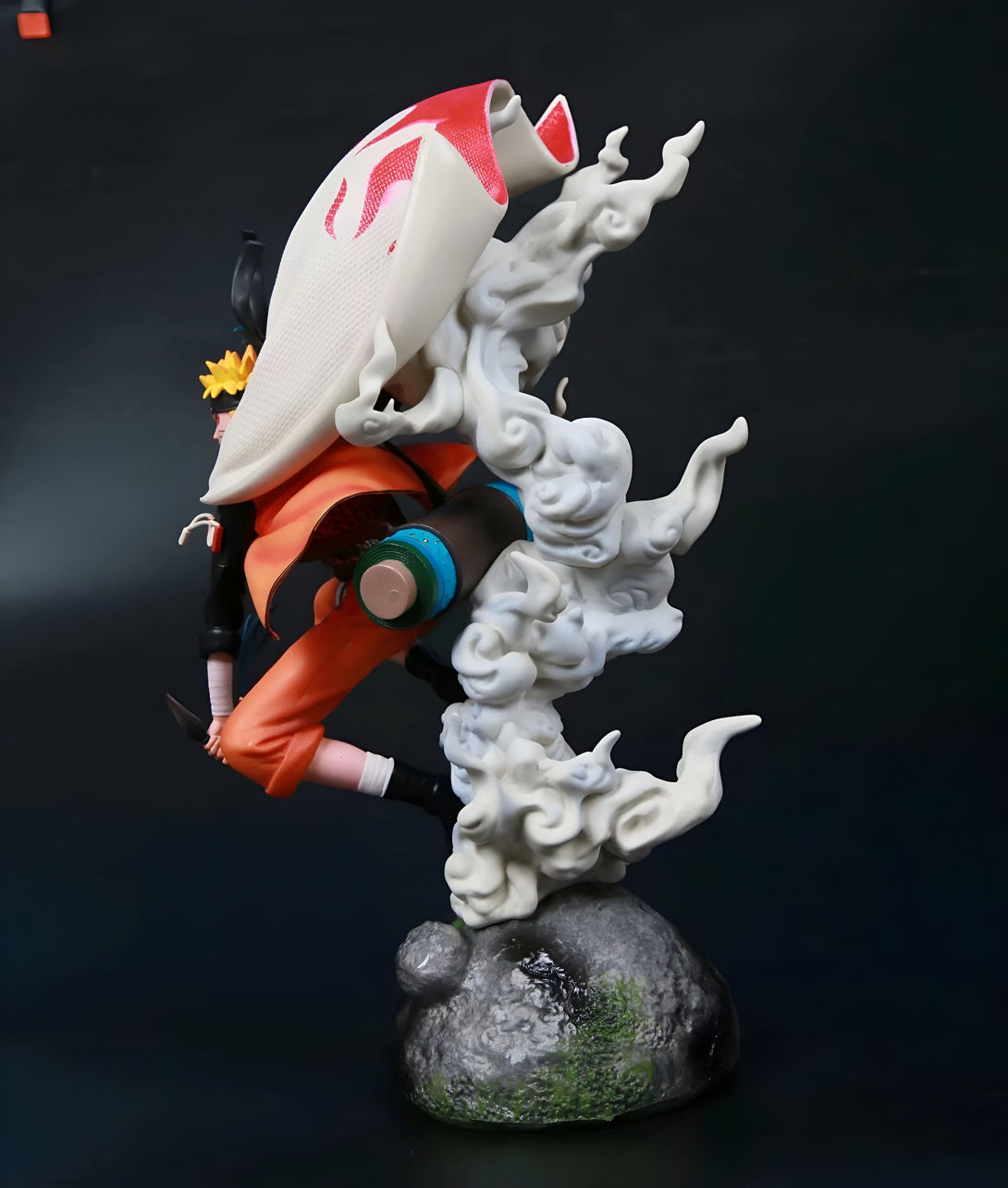 Statue de Naruto en mode sage des six chemins, flottant dans les airs sur une base rocheuse avec des nuages blancs.