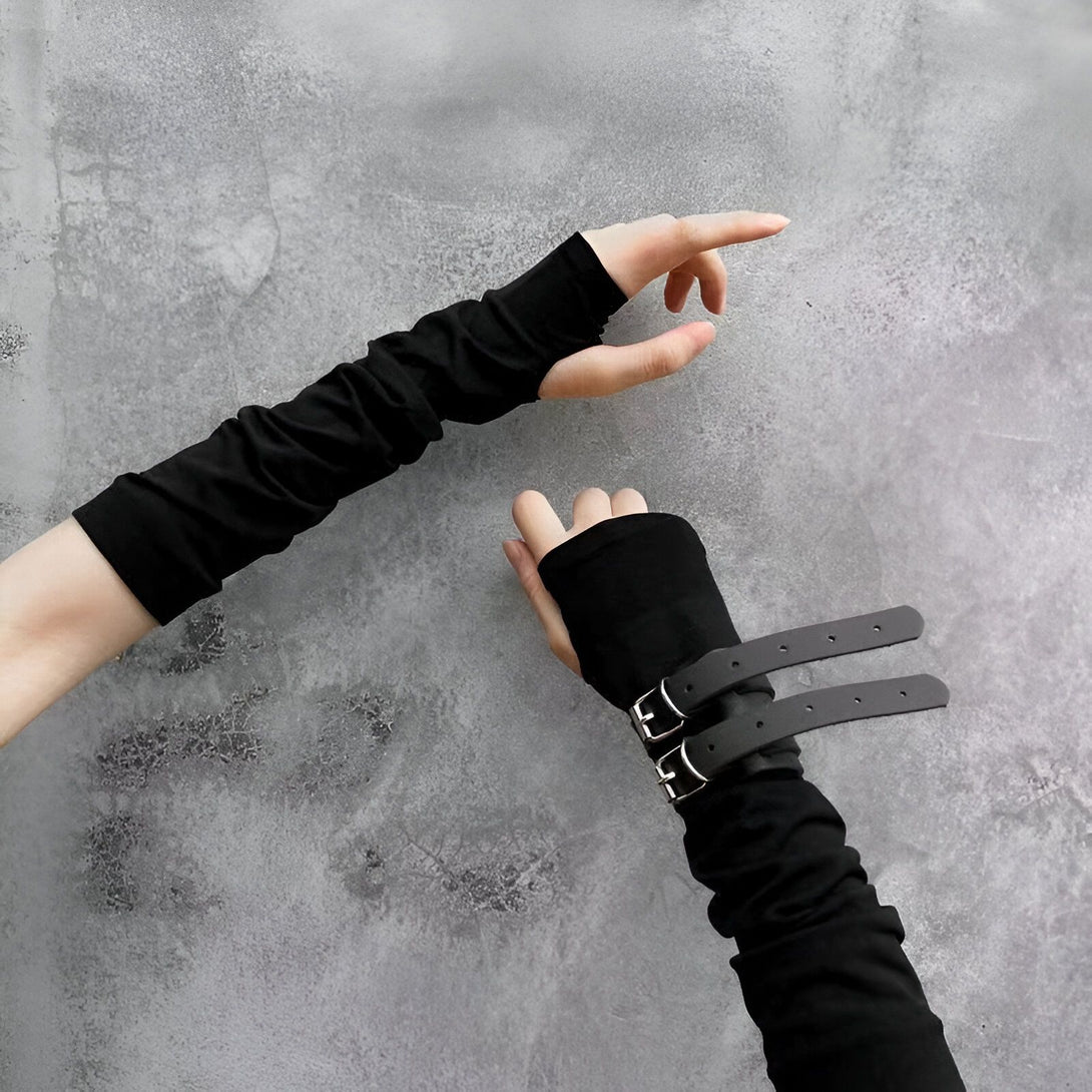 Deux paires de manchettes noires, l'une avec une boucle en métal et l'autre sans, posées sur un fond gris.