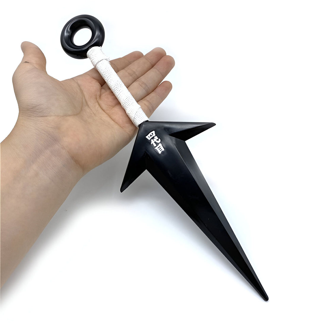 Une main tenant un kunai noir avec une corde blanche et l'inscription "影分身" en japonais, un accessoire de cosplay Naruto.