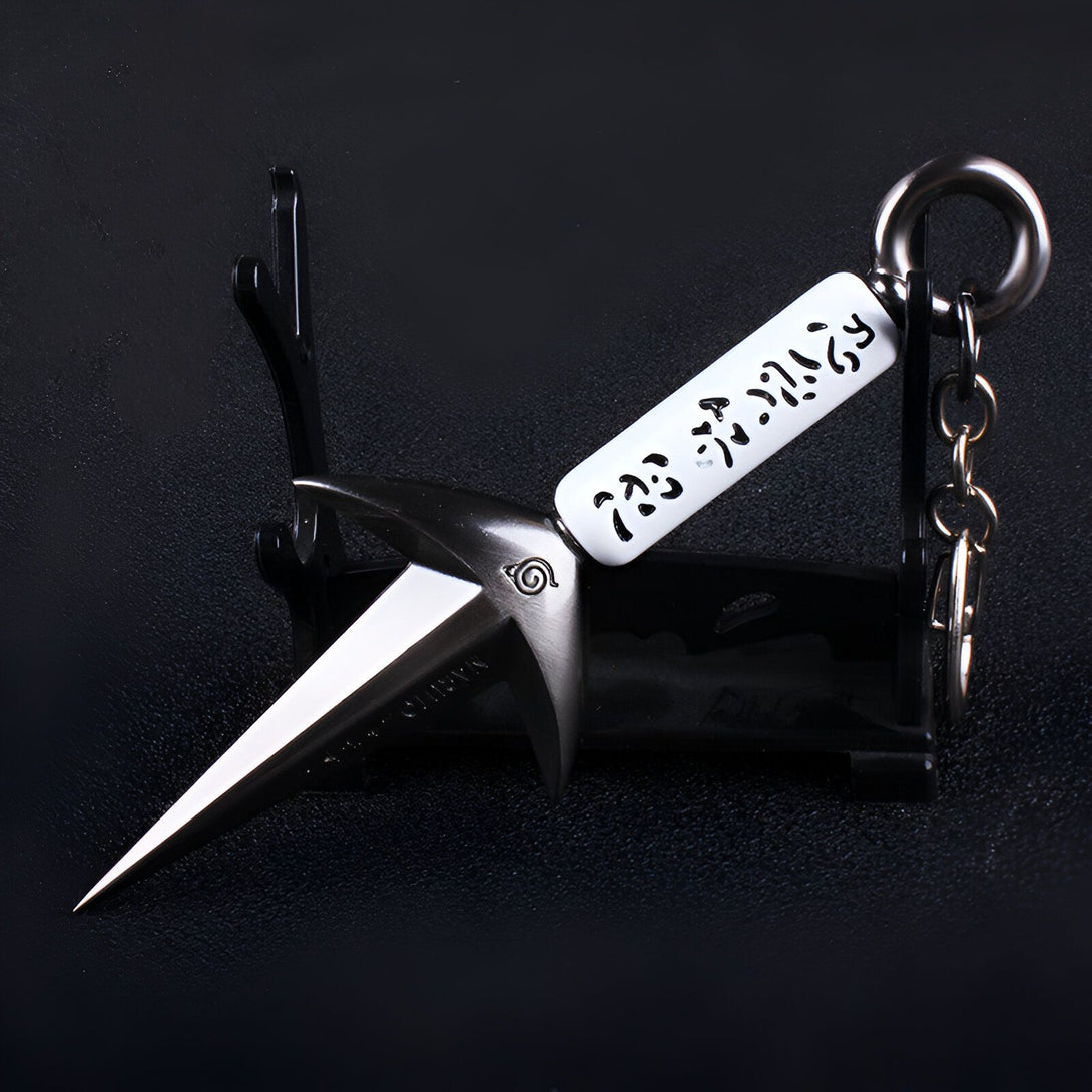 Porte-clés en forme de kunai de Naruto avec le symbole du village caché de Konoha et des caractères japonais gravés.