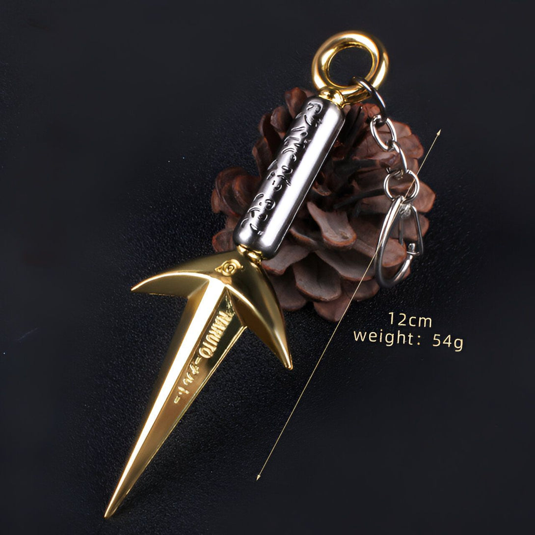 Porte-clés en forme de kunai en or et argent, avec inscription en japonais, mesurant 12 cm et pesant 54 g.