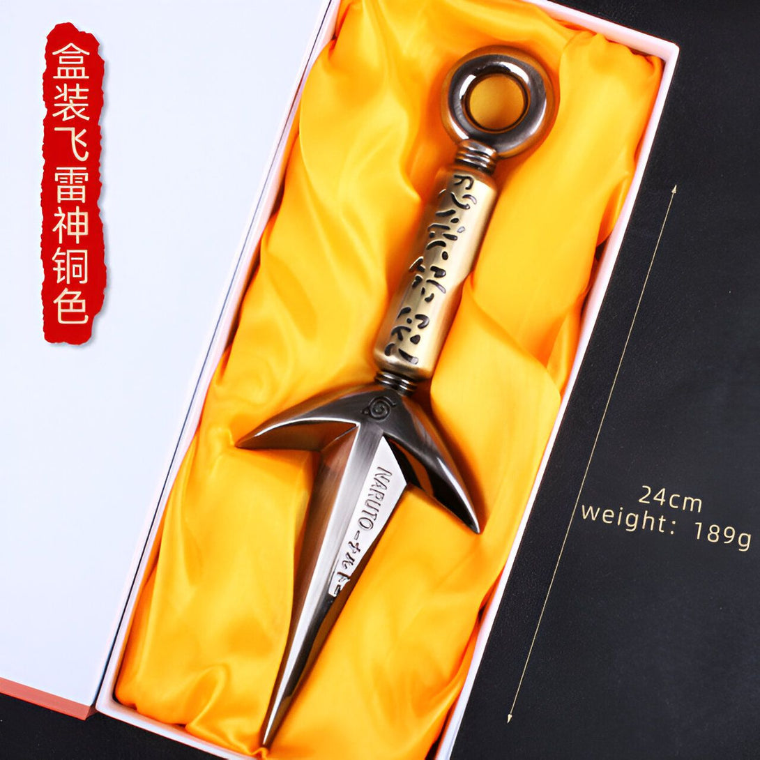 Un kunai en métal, l'arme emblématique de Naruto, présenté dans une boîte de présentation jaune. Le kunai est décoré de kanji et porte l'inscription "Naruto Uzumaki".
