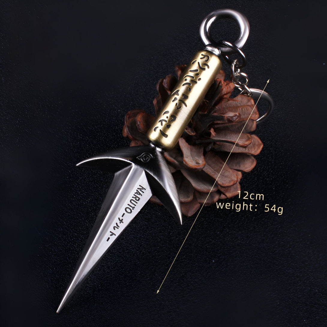 Porte-clés en métal représentant le kunaï de Naruto, avec inscription "Naruto" et symboles japonais. Le kunaï est de couleur argentée, avec un manche en or et un anneau pour clés.