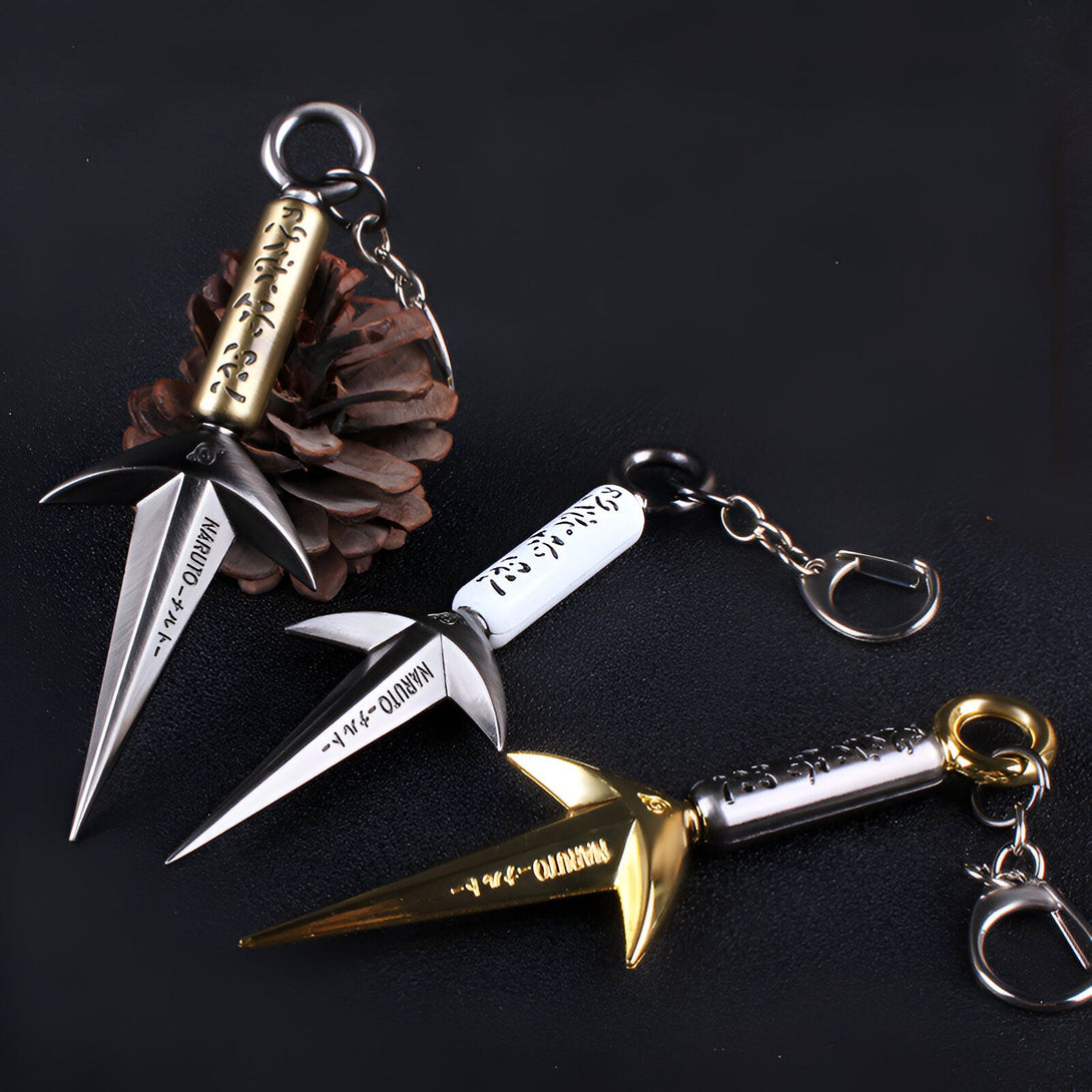 Trois porte-clés en forme de kunai de Naruto, avec les inscriptions "Naruto" en japonais, en or, argent et blanc.  Ces accessoires de collection sont parfaits pour les fans de l'anime.