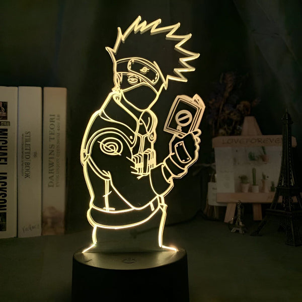 Lampe 3D de Kakashi Hatake, personnage du manga Naruto, tenant un parchemin. Cette lampe est parfaite pour les fans de Naruto et ajoutera une touche de style à n'importe quelle pièce.