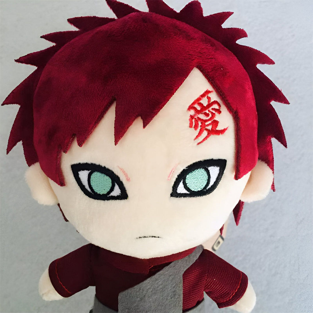 Peluche en forme de Gaara, personnage de l'anime Naruto, avec ses cheveux roux, ses yeux verts et le symbole "Amour" sur son front.