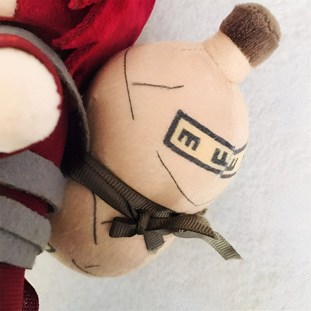 Peluche de Naruto représentant le personnage de Jiraiya avec son bandeau et son inscription "M" en japonais.